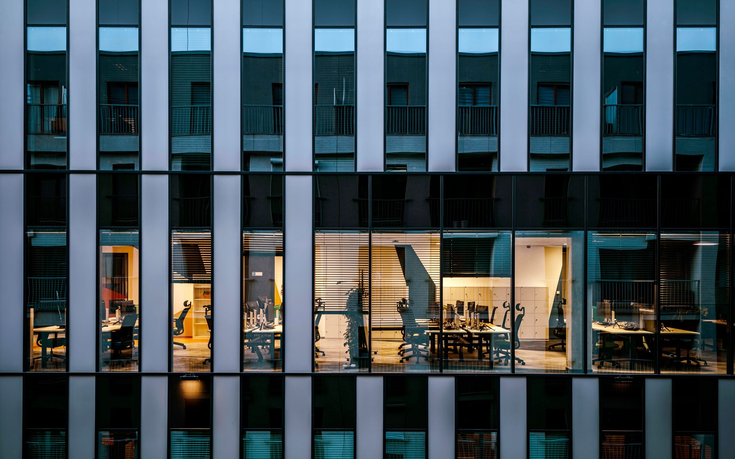 A commercial building at dusk with its interior lights on
